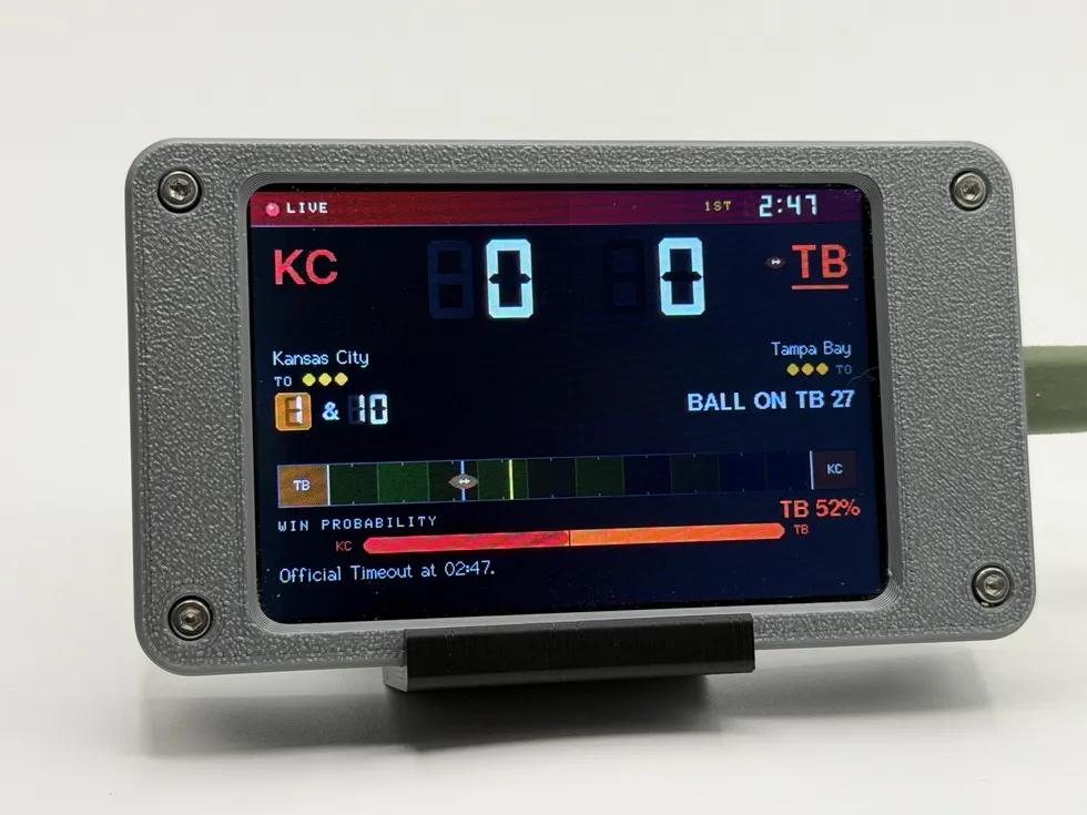 Pro Football Scoreboard showing a live game in the gray enclosure: score, quarter and game clock, down and distance, a field strip with the ball, and a win-probability bar